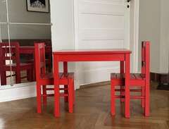 rött barnbord med stolar i trä