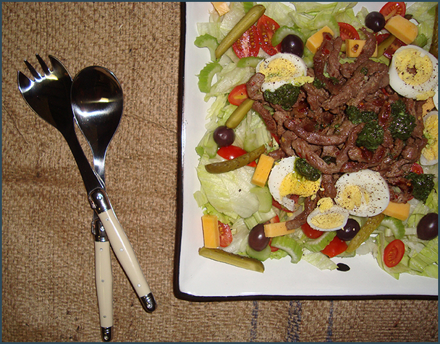 Green salad with beef strips and basil pesto