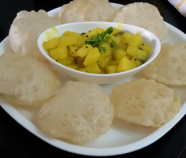 Luchi or Bengali Style Poori served with Aloo Chorchori or Potato Curry with Kalonji or Nigella seeds ( Kalojeera )