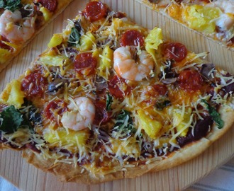 Pizza de camarão, linguiça, azeitonas e ananás aromatizada com manjericão